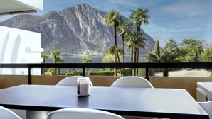 A dining area with a table and chairs, a candle, and a view of mountains and palm trees.