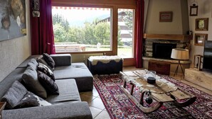 Ett vardagsrum med en soffa, ett soffbord, en öppen spis och en tv.