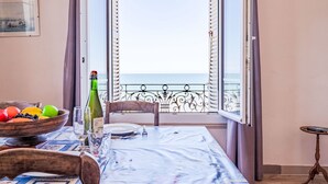 Une table à manger avec vue sur la mer, donnant sur un balcon ouvert.