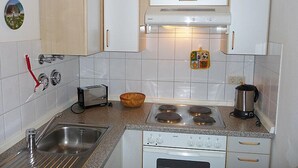 A kitchen with white cabinets, a gas stove, a toaster, a sink, and a kettle. - Schwarzwaldblick by Interhome (Schonach)