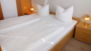 A neatly made bed with white linens and two bedside lamps. - Schwarzwaldblick by Interhome (Schonach)