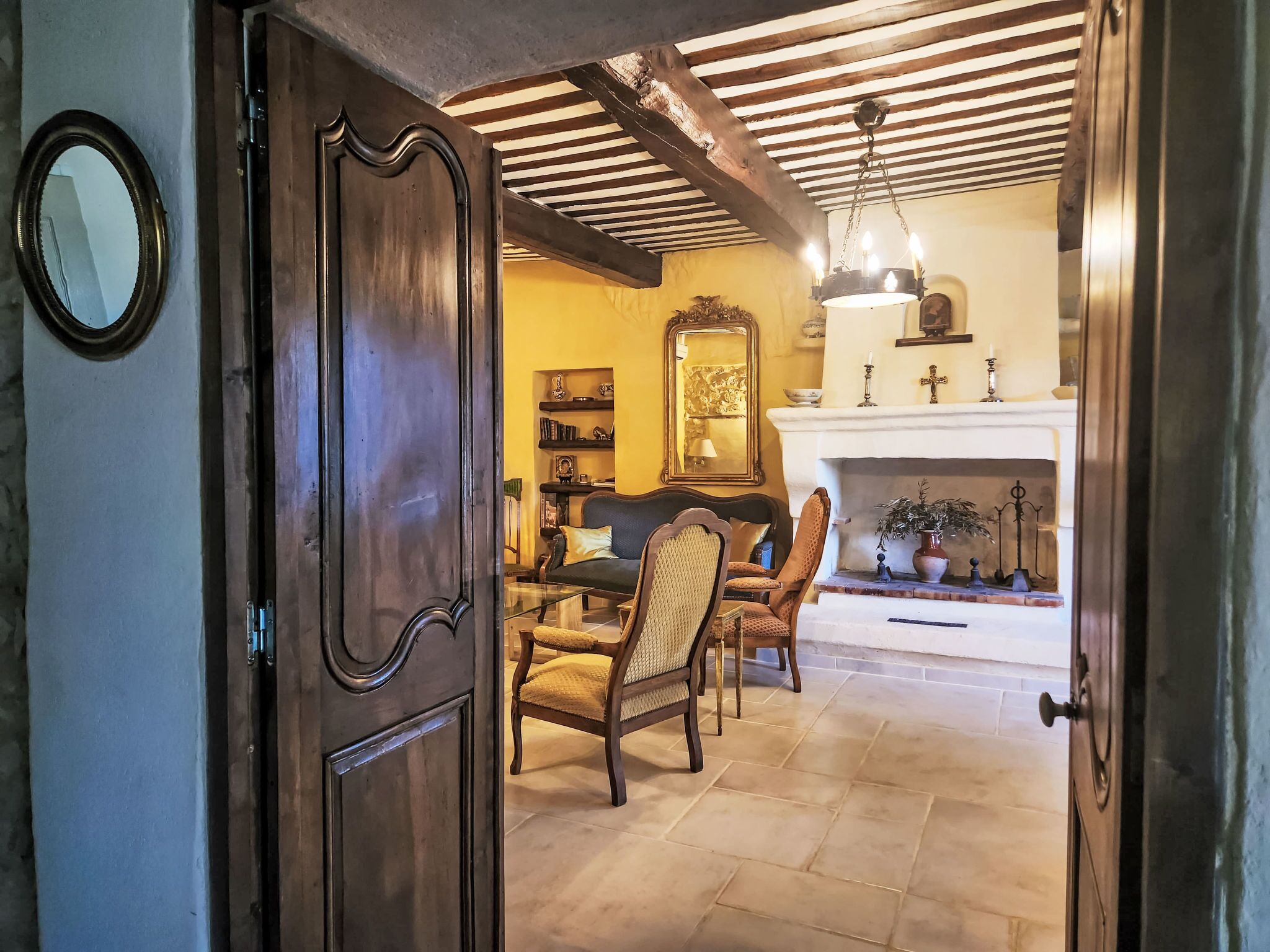 A traditional room with a wooden door, a fireplace, and a dining area with chairs and a table.
