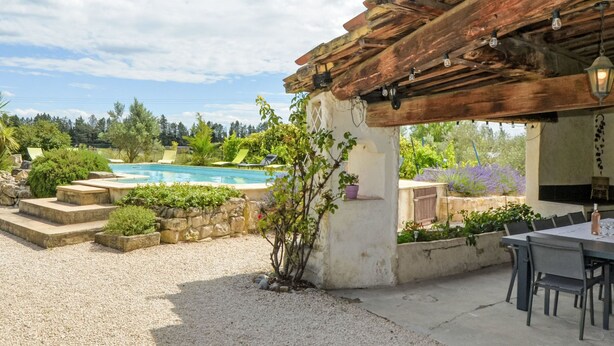 Ein Poolbereich mit Pergola, Sitzgelegenheiten und Blick auf den Pool.