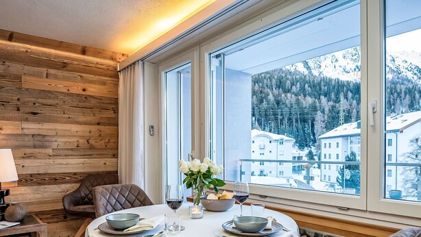 A dining area with a table set for two, a view of a snowy mountain, and a wooden wall. - Chesa Fleury by Interhome (St. Moritz)