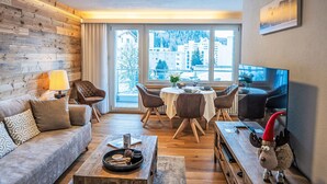 A modern living room with a sofa, coffee table, and dining area. - Chesa Fleury by Interhome (St. Moritz)