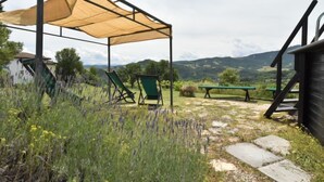 A covered outdoor seating area with chairs and a table, surrounded by a natural landscape with mountains in the background. - Vacation home Busani by Interhome (Salsomaggiore Terme)