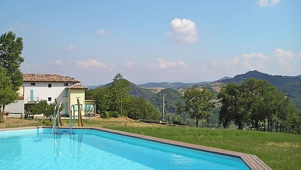A swimming pool with a view of a mountain range and a building with a tiled roof. - Vacation home Busani by Interhome (Salsomaggiore Terme)
