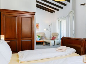 Una habitación de hotel con cama, una silla, un escritorio y un armario.