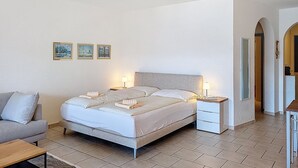 A bedroom with a bed, bedside tables, a sofa, and a small table.