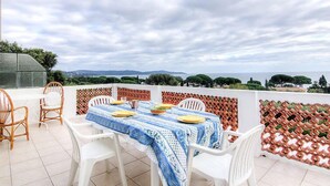 A terrace with a table set for four, surrounded by white chairs, overlooking a scenic landscape. - Riva Bella by Interhome (Cavalaire)
