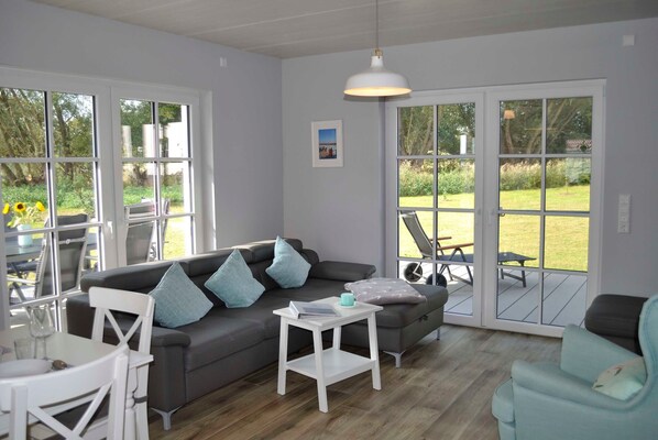 A modern living room with a grey sofa, white side table, and a teal armchair. - Vacation home Ankerplatz for rent in the Baltic seaside resort of Rerik - Holiday home Ankerplatz (Rerik (Ostseebad))