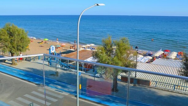 A beach with umbrellas and people, a street with a blue bike lane, and a clear blue sky. - Appartamento 2 by Interhome (Terracina)