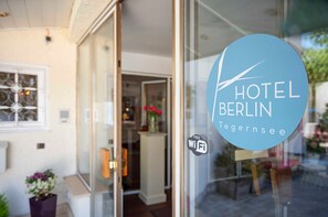 A hotel entrance with a glass door, a 'Free WiFi' sign, and a logo for 'Hotel Berlin Tegernsee'.