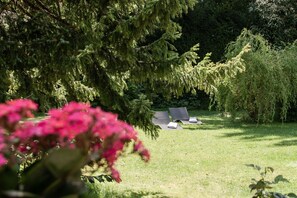 Ein Garten mit Rasen, Bäumen und einer Sitzgelegenheit mit Stühlen.