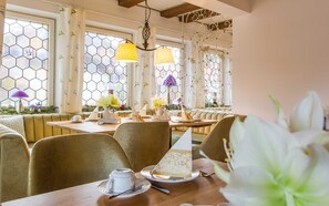A dining area with hexagonal windows, a wooden table, and a bench.