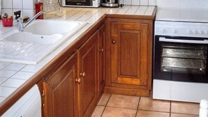 A kitchen with a sink, wooden cabinets, a stove, and a microwave. - Comfortable cottage with large private garden and WIFI (Channay-sur-Lathan)