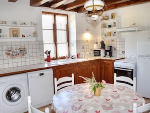 Une cuisine avec des meubles en bois, un réfrigérateur blanc, un four à micro-ondes, une cuisinière et un lave-linge.