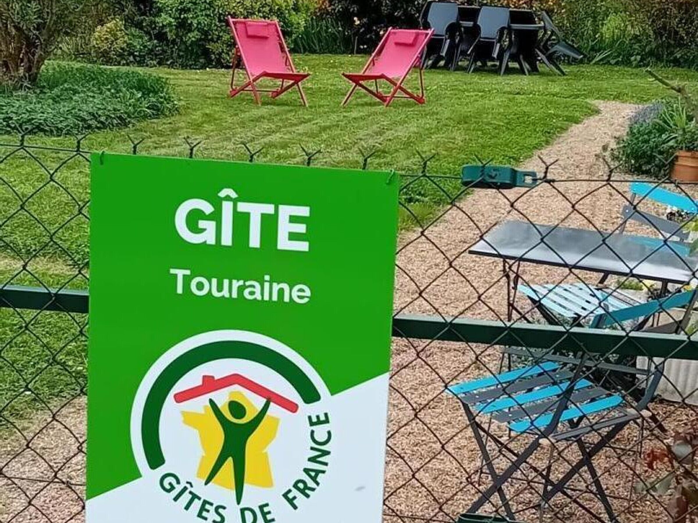 A sign for GITE Touraine with a logo of a person holding a house, indicating a campsite or holiday park.