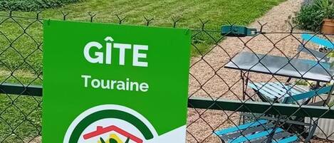 A sign for GITE Touraine with a logo of a person holding a house, indicating a campsite or holiday park.