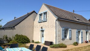 A two-story house with a balcony, a small garden, and outdoor seating. - Comfortable cottage with large private garden and WIFI (Channay-sur-Lathan)