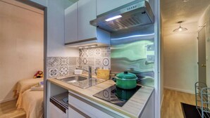 A compact kitchen with a built-in stove, a sink, and a backsplash with patterned tiles. - Vostok Zodiaque by Interhome (Le Corbier)