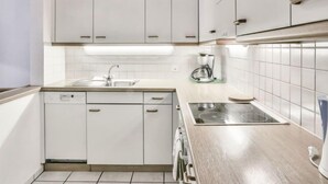 A modern kitchen with white cabinets, a stainless steel sink, and a coffee maker. - Chalet Abendrot apARTments by Interhome (Grindelwald)
