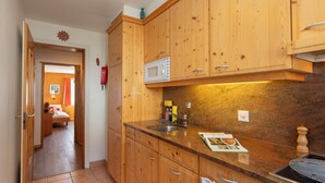 Une cuisine avec des meubles de rangement en bois, un four à micro-ondes, un évier et une cuisinière.