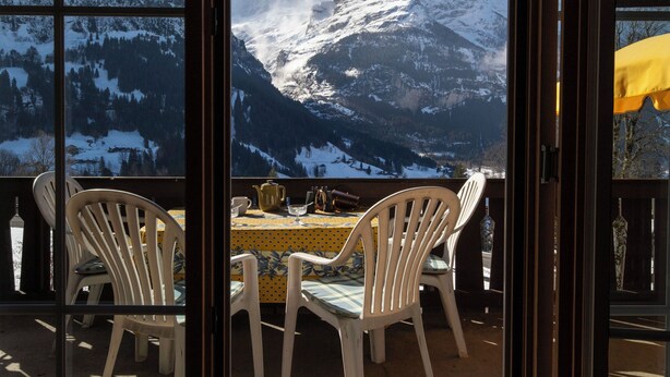 Une vue sur la montagne, visible à travers une fenêtre, avec une table et des chaises.