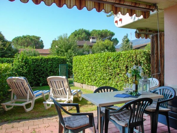 Une terrasse extérieure avec une table et des chaises, entourée de verdure et offrant une vue sur les maisons au loin.