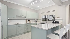 A modern kitchen with light green cabinets, a central island, and a built-in oven. - Position, space and privacy (Nelson Bay)