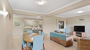 A modern living room with a dining area, a kitchen in the background, and a TV on a stand. - Position, space and privacy (Nelson Bay)