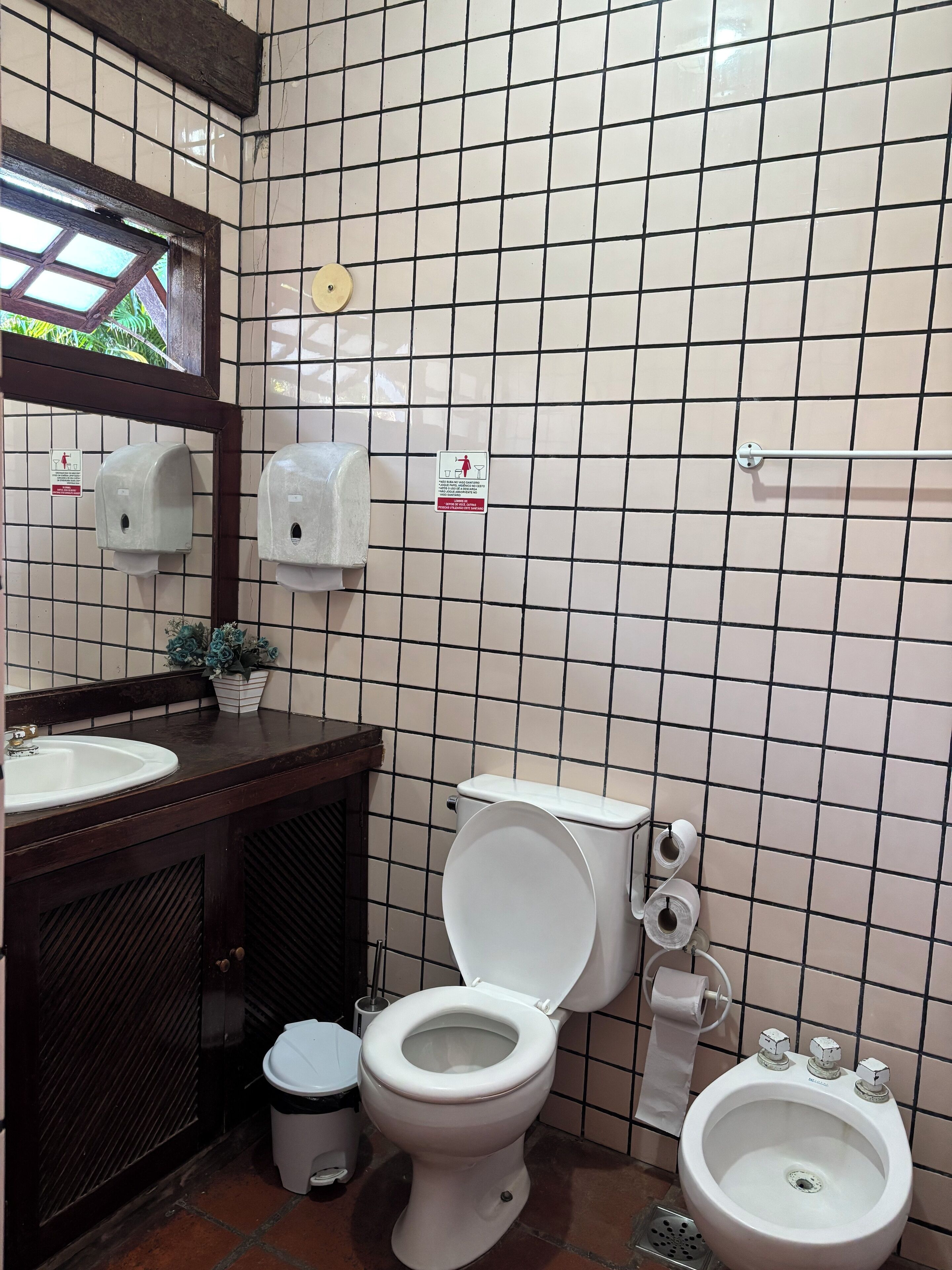 A bathroom with a toilet, bidet, sink, and hand dryer.
