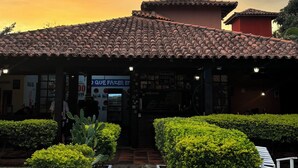 A building with a tiled roof, a paved entrance, and well-maintained hedges. - Numa Boa Hostel (Búzios)