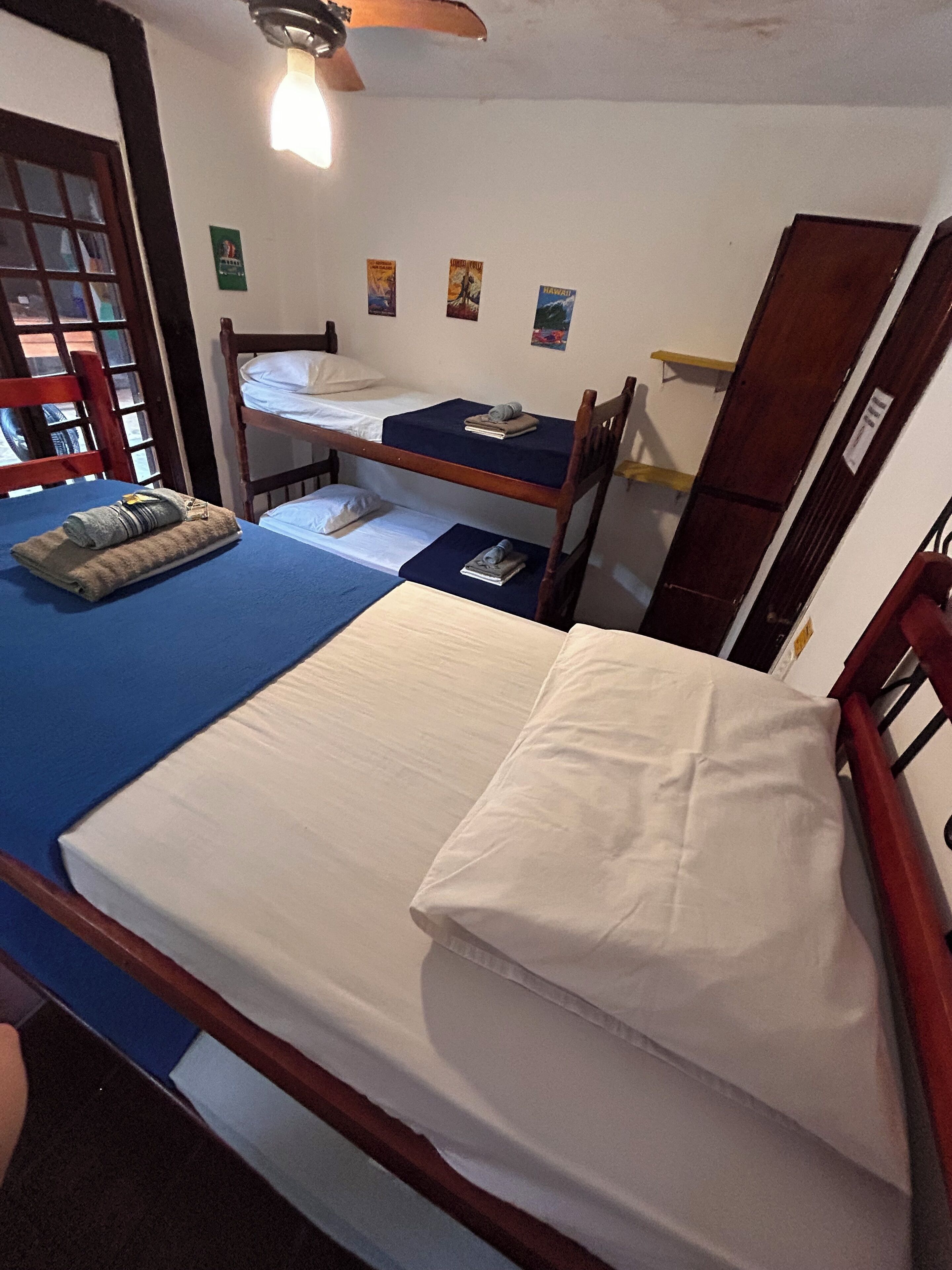 A dormitory-style room with bunk beds, a desk, and a chair.