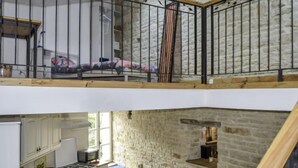 Un appartement de style « loft » avec une cuisine et un balcon. La cuisine est équipée de meubles blancs, d’une cuisinière et d’un évier. Le balcon est doté d’une rambarde en métal et offre une vue sur l’extérieur.