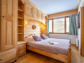 Un dormitorio de madera con cama, estanterías empotradas y ventana con vistas.