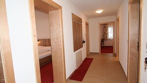 A hallway with wooden flooring, a red carpet, and a bed in one room. - Pfeifer by Interhome (Pians)