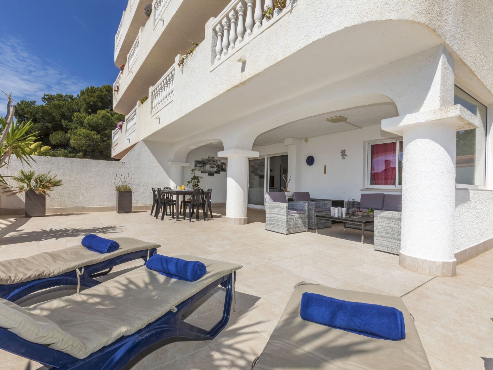 A sunlit outdoor area with lounge chairs, a dining table, and a seating area with sofas.