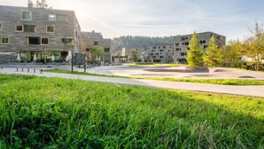 Un moderno complejo de edificios con varias unidades residenciales, un patio central y zonas verdes circundantes.