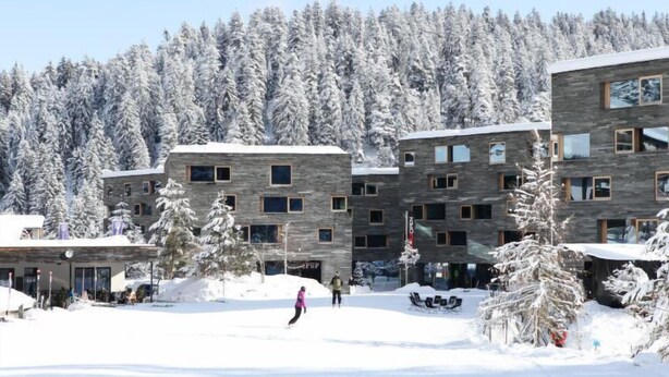 Un edificio moderno con varios pisos, rodeado de árboles cubiertos de nieve.