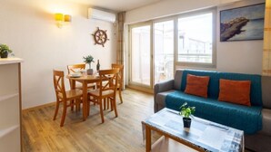 Een woonkamer met een eettafel, stoelen, een bank en een salontafel.
