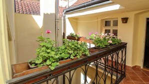 Een balkon met plantenpotten en een metalen hekwerk.