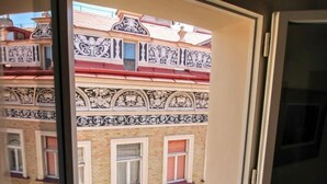 Een raam met uitzicht op een gebouw met decoratieve zwart-wit patronen op de gevel.