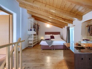 Une chambre avec un plafond en bois, un lit avec une literie blanche, une table de chevet et une armoire.