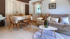 A cozy dining area with a wooden table and chairs, a sofa, and a small side table with a vase. - Vacation home Ana by Interhome (Rovinj/Rovinjsko Selo)
