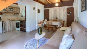 A cozy living room with a sofa, a dining table with chairs, a kitchen area with cabinets and appliances, and a wooden staircase. - Vacation home Ana by Interhome (Rovinj/Rovinjsko Selo)