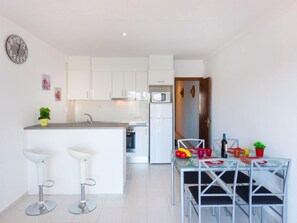 Uma cozinha moderna com armários brancos, micro-ondas e uma área de jantar com mesa e cadeiras.