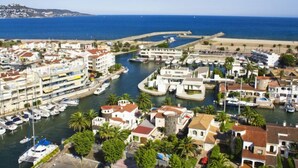 A coastal marina with boats docked, surrounded by residential buildings and palm trees. - Sant Maurici by Interhome (Empuriabrava)