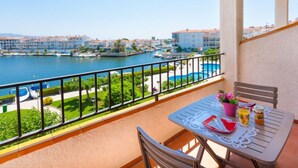 A balcony with a table and chairs, overlooking a marina with boats and a swimming pool. - Sant Maurici by Interhome (Empuriabrava)