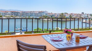 A balcony with a table set for two, overlooking a marina with boats and buildings in the background. - Sant Maurici by Interhome (Empuriabrava)